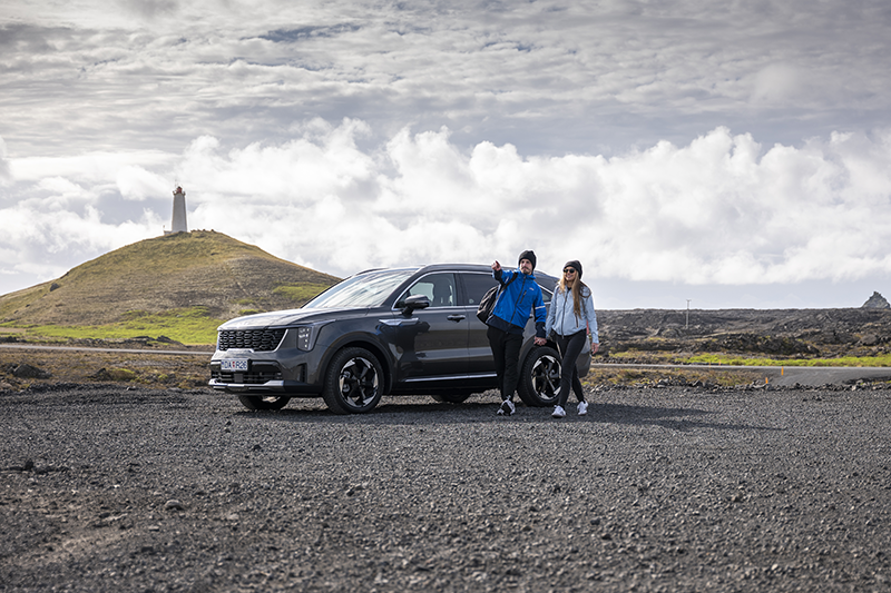 Couple standing beside a rental car from Holdur car rental in Iceland